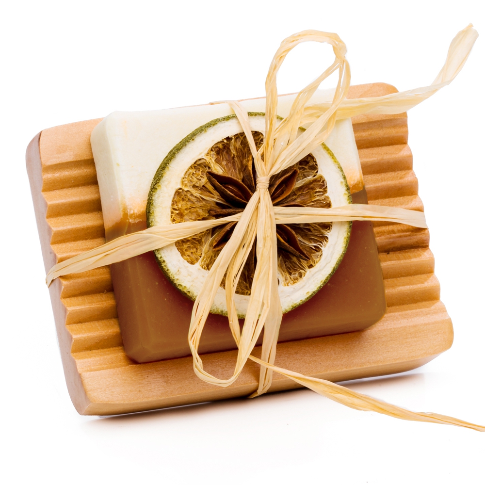 ZimtVanille-Orangen Seife auf einer Kiefer Seifenschale gebunden. Als Deko ist eine getrocknete Orangenscheibe mit Bastband befestigt.