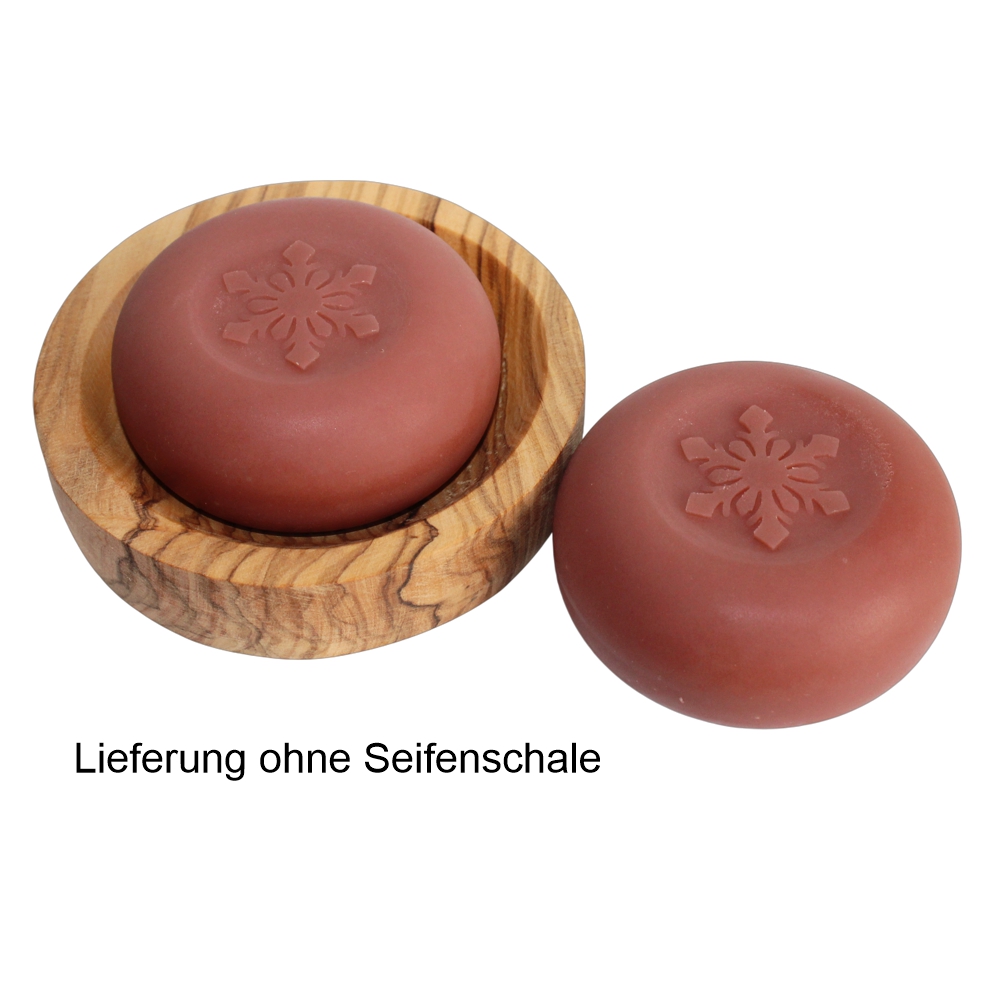 Rundes Stück Seife in Rot mit einer Schneeflocke eingestempelt auf einer Olivenholz Seifenschale gelegt.