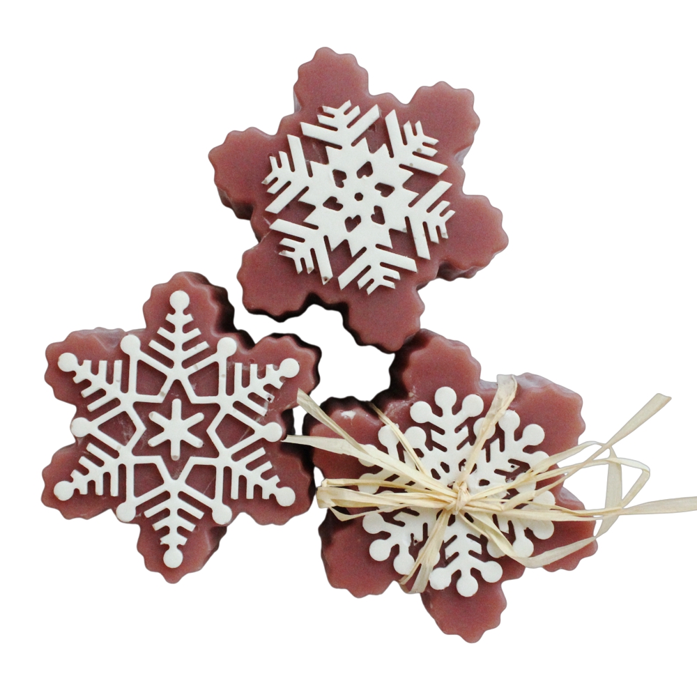 Drei violette schneeflockenförmige Seifenstücke mit weißen kunstvollen Eiskristallen oben auf.